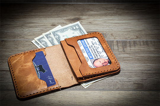 An RFID blocking bifold leather wallet open showing cards and cash.