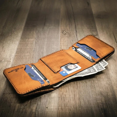 Trinity western trifold wallet in saddle tan leather, featuring multiple card slots and a cash compartment, showcasing a rustic and handcrafted design.
