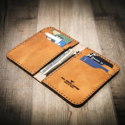 Handmade western style vertical wallet in saddle tan, open with cards and cash inside.
