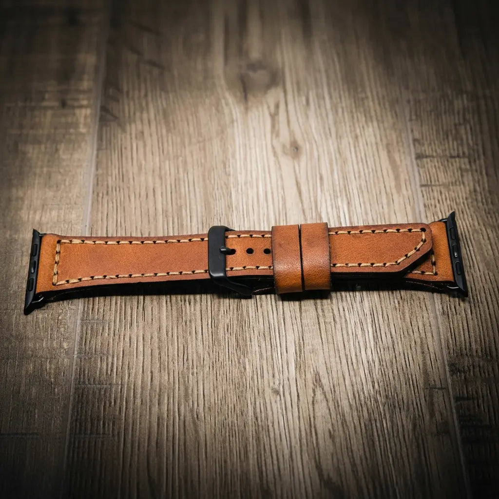 Brown full-grain leather Apple Watch band with black buckle and contrast stitching on wood surface.