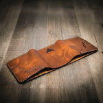 Trinity western trifold wallet in chestnut brown leather, facedown to show off the intricate stitching and a smooth finish, handmade in the USA.
