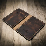 Handmade leather wallet in walnut brown color with visible stitching, branded "Bull Sheath Leather" and "Made in Texas," on a wooden surface.