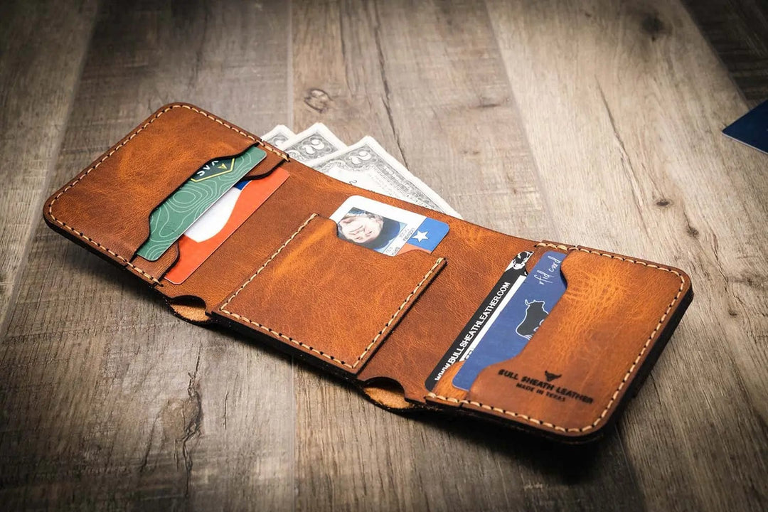 Trinity western trifold wallet in chestnut brown leather, featuring multiple card slots, a cash compartment, and a clear ID window, displayed open with cards and cash inside.
