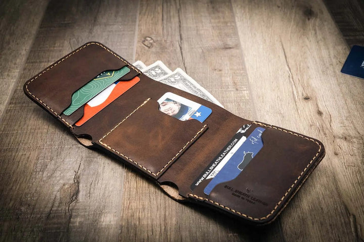 Trinity western trifold wallet in walnut brown leather, featuring multiple card slots and a cash compartment, displayed open with cards and cash inside.