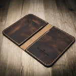 Handmade leather wallet in walnut brown color with visible stitching, branded "Bull Sheath Leather" and "Made in Texas," on a wooden surface.
