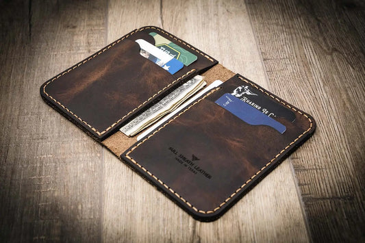 Handmade western vertical leather wallet in walnut brown color, open to show card slots and cash.
