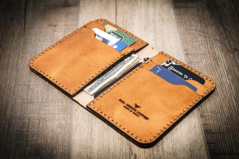 Handmade western style vertical wallet in saddle tan, open with cards and cash inside.