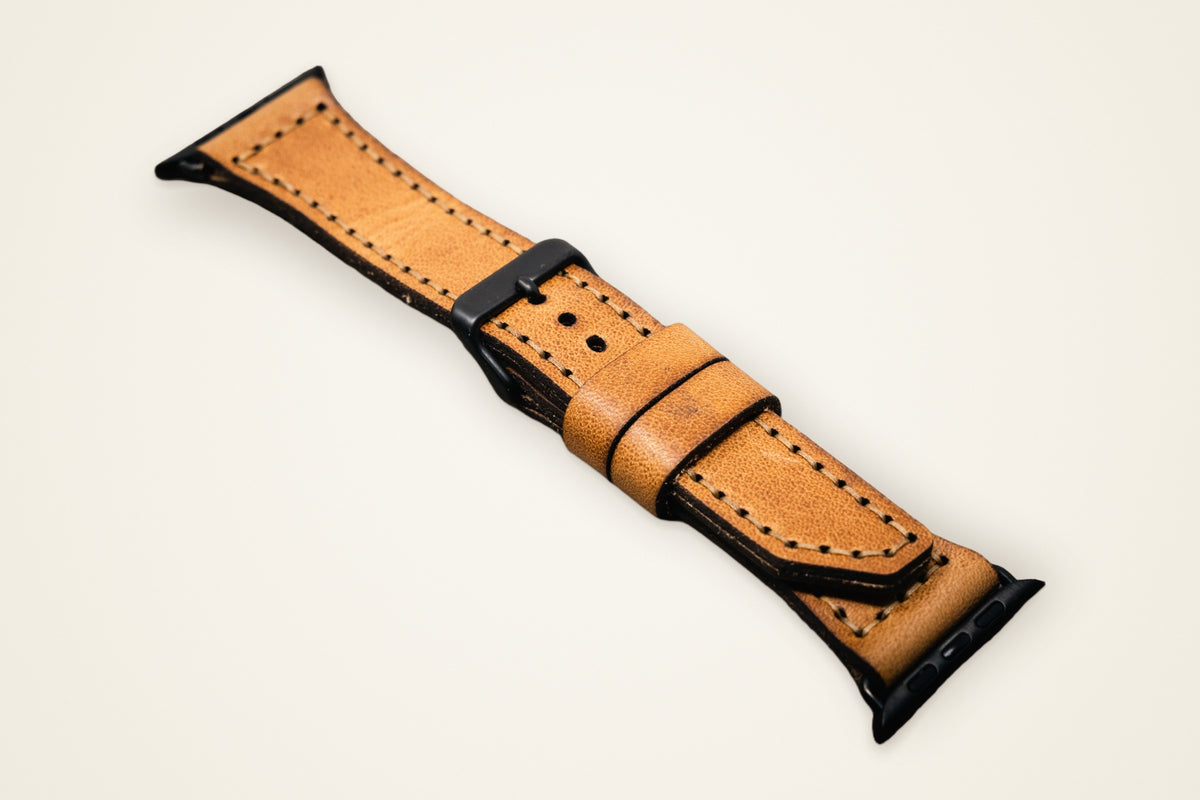Apple Watch Leather Band on a cream background, showing its precision connectors, stitched by hand, full-grain horween leather