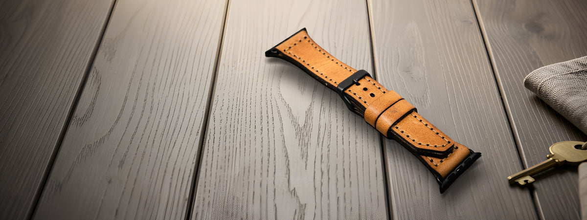 Apple Watch Leather Band in tan full-grain leather open on a dark oak table beside keys