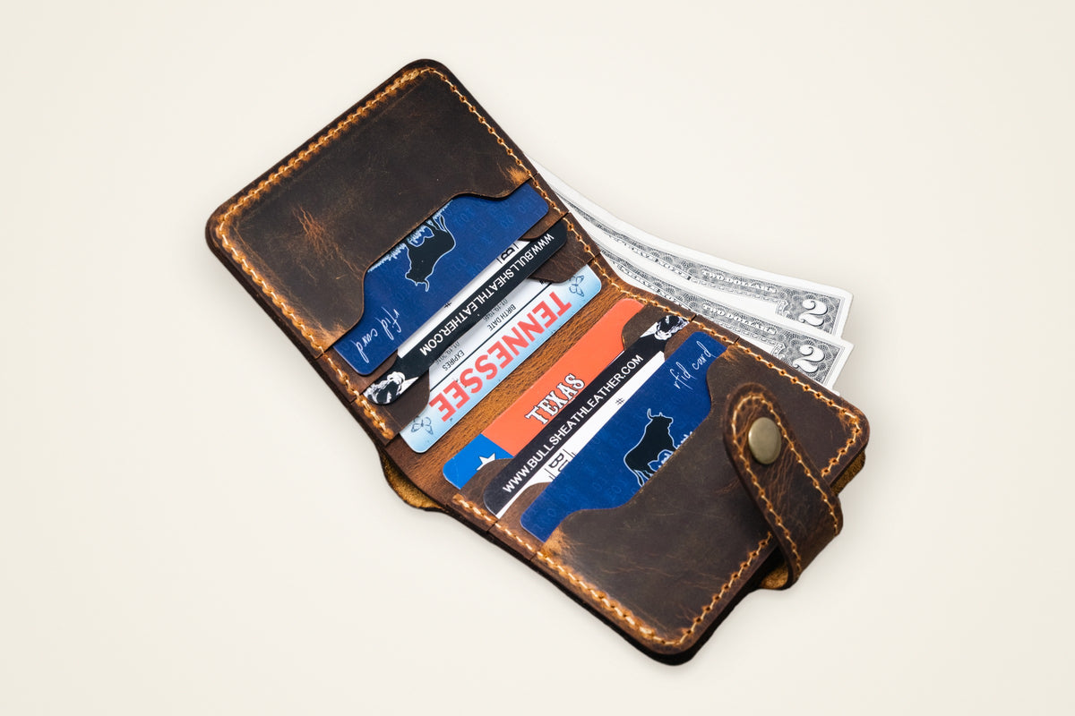 Glory Snap Bifold Wallet on a cream background, showing its snap closure, six card slots, full-width cash pocket, horween full-grain leather