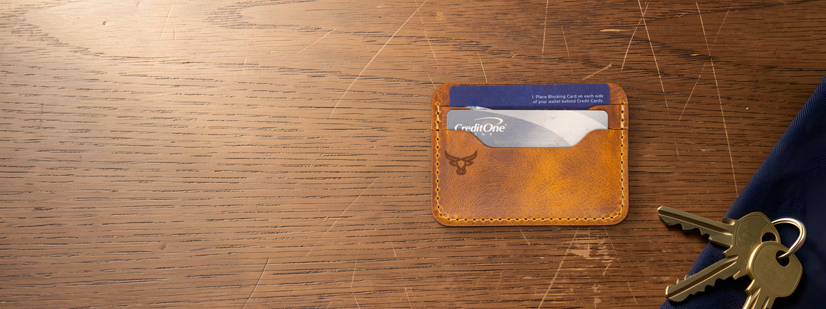Pflugerville Card Wallet in chestnut full-grain leather holding cards on an oak table beside keys
