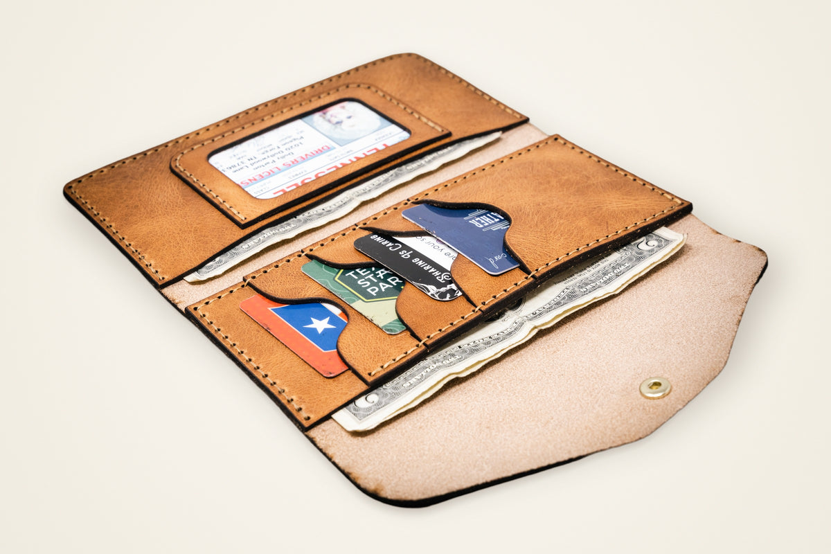 Sugar Land Clutch Wallet on a cream background, showing its four card slots, two vertical pockets, wraps and folds flat, full-grain horween leather
