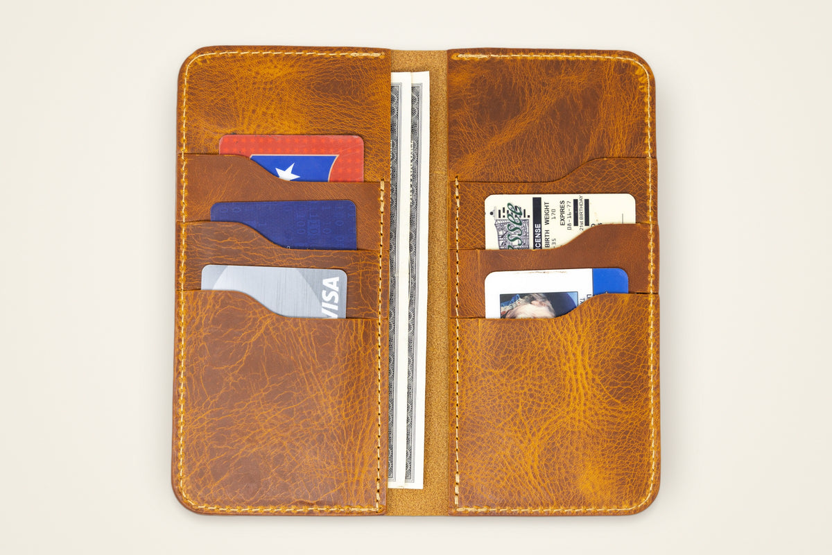 The Houstonian Long Wallet on a cream background, showing its six card slots, two full-length cash pockets, horween full-grain leather, handmade in mansfield, texas