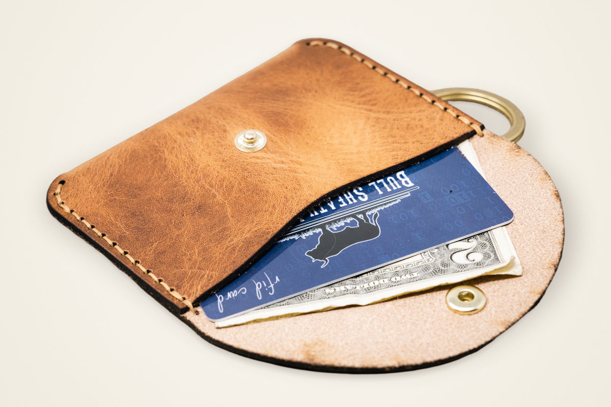 The Richmond on a cream background, showing its rides on your key ring, compact snap pocket, snap closure, full-grain horween leather
