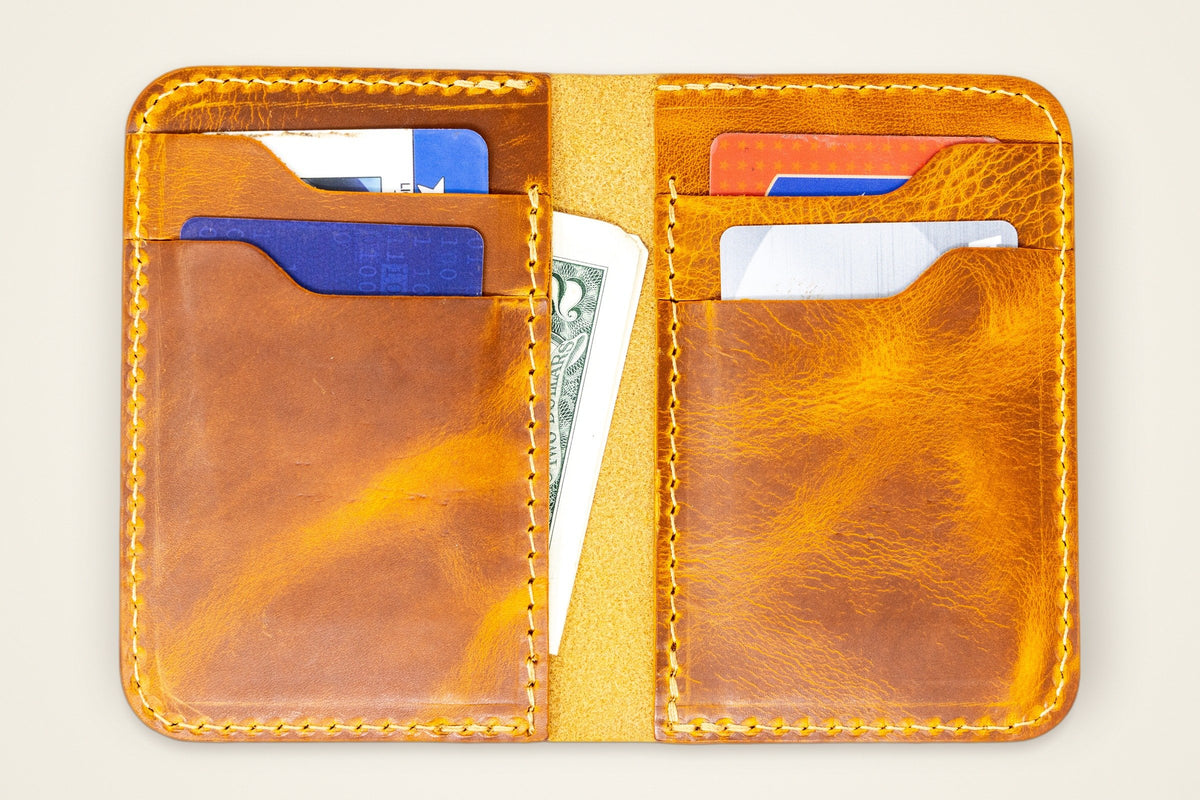 Tyler Vertical Wallet on a cream background, showing its four vertical card slots, two interior pockets, holds 12+ cards, horween full-grain leather