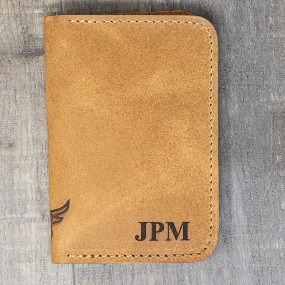 Tan leather bifold wallet with the initials JPM engraved in serif capitals in the lower right corner