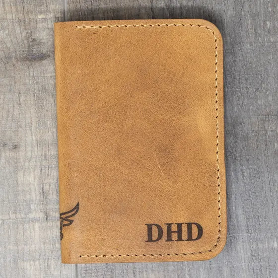 Tan leather wallet with the initials DHD engraved in bold serif capitals in the lower right corner